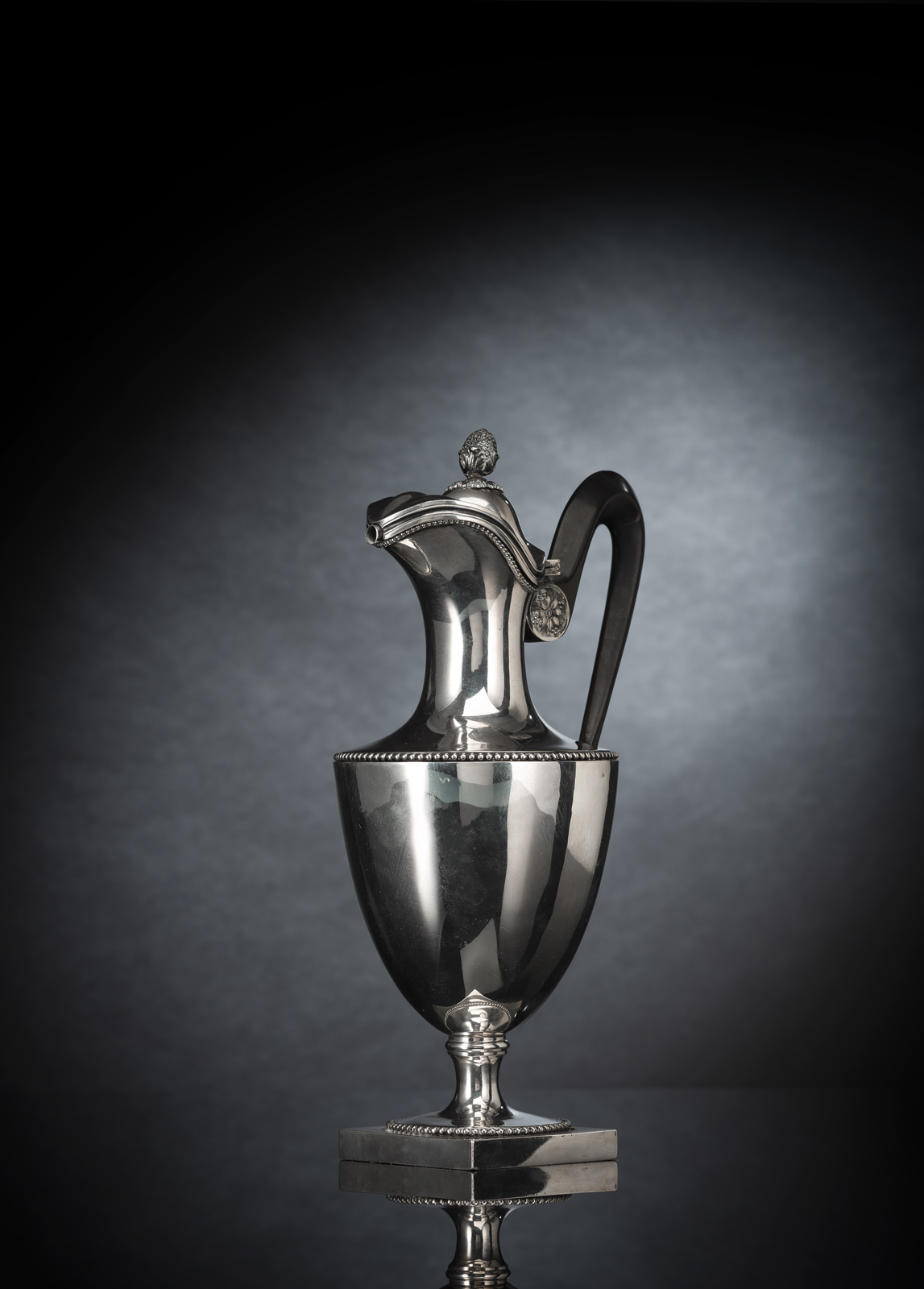 Silber, ovoider Korpus mit Perlbandfriesen, Röhrenausguss und ebonisiertem Holzhenkel. Feingehaltsstempel für 800er Silber mit Hahn, Meisterzeichen wohl von Gabriel Germain Dutalis (?, etwas verschlagen). 784 gr. Minim. verbeult. Silber, ovoider Korpus mit Perlbandfriesen, Röhrenausguss und ebonisiertem Holzhenkel. Feingehaltsstempel für 800er Silber mit Hahn, Meisterzeichen wohl von Gabriel Germain Dutalis (?, etwas verschlagen). 784 gr. Minim. verbeult.