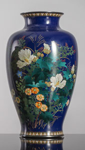 <b>Feine Cloisonné-Vase mit verschiedenen Blüten wie Hibnisku und Astern neben Gräsern auf blauem Fond</b>