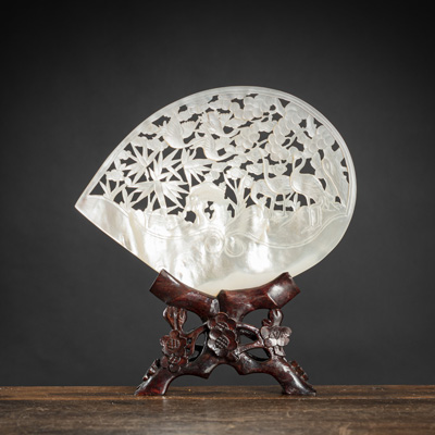 <b>A SHELL CARVED IN OPENWORK WITH CRANES AMIDST PINE TREES, BAMBOO AND PEONIES ON WOOD STAND</b>